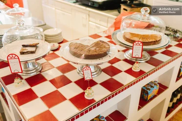 GundolfS Drei Kuchen auf roten und weißen Kacheln, umgeben von kleinen dekorativen Süßigkeiten.