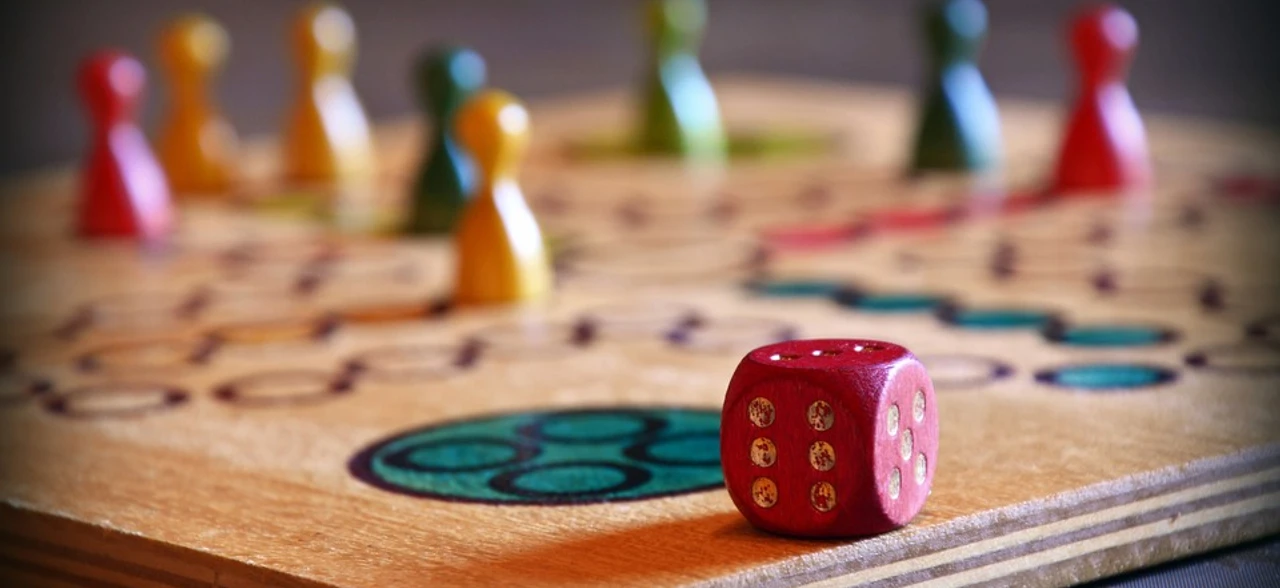 Beispielbild Holzspielbrett mit würfel und bunten Spielfiguren, ein Symbol für geselliges Beisammensein.Wooden game board with dice and colorful game pieces, a symbol for social get-togethers.Spilleplade af træ med terninger og farverige brikker, et symbol på socialt samvær.Houten speelbord met dobbelstenen en kleurrijke speelstukken, een symbool voor sociale bijeenkomsten.