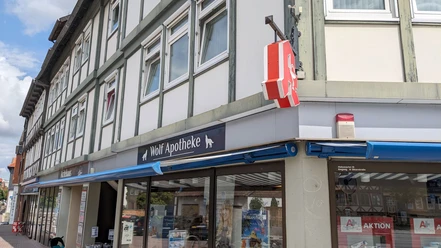Ein Eckhaus mit hellem Fachwerk, im Erdgeschoss die Wolf Apotheke
