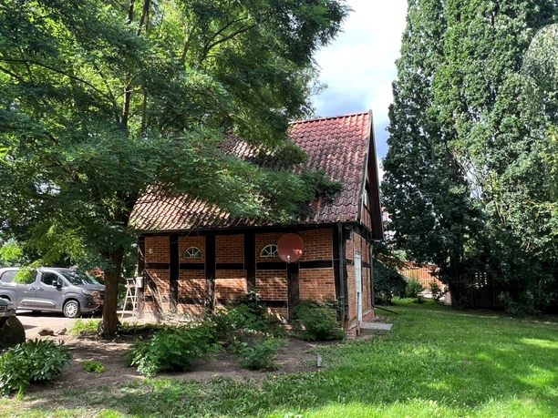 Rittergut Wulzen Ehemaliges Fachwerkgebäude inmitten von Grünflächen, umgeben von Bäumen, mit rotem Ziegeldach.
