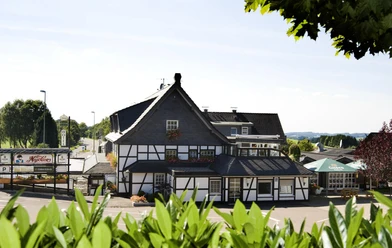 Außenansicht des Landhotel Napoleon mit Fachwerkhaus, Terrasse und grüner Umgebung