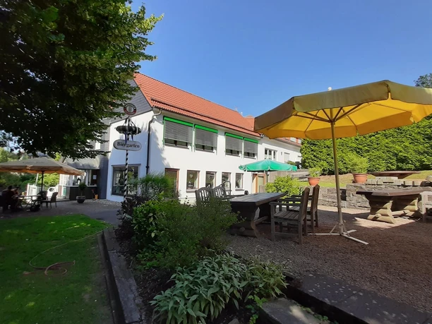 An sonnigen Tagen verlockt der große Biergarten im Sonniger Biergarten am Landgasthof Tönnes mit gelbem Schirm und Holztischen