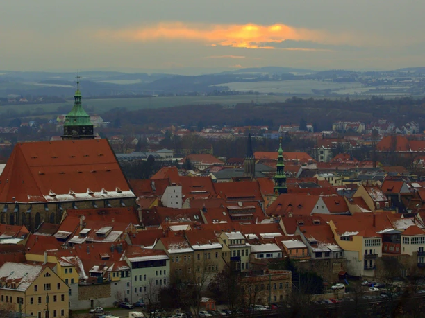 Pohled na kostel Panny Marie - Canaletto View Pohled na město s červenými střechami a kostelem v popředí, v pozadí zatažená obloha s oranžovým západem slunce.