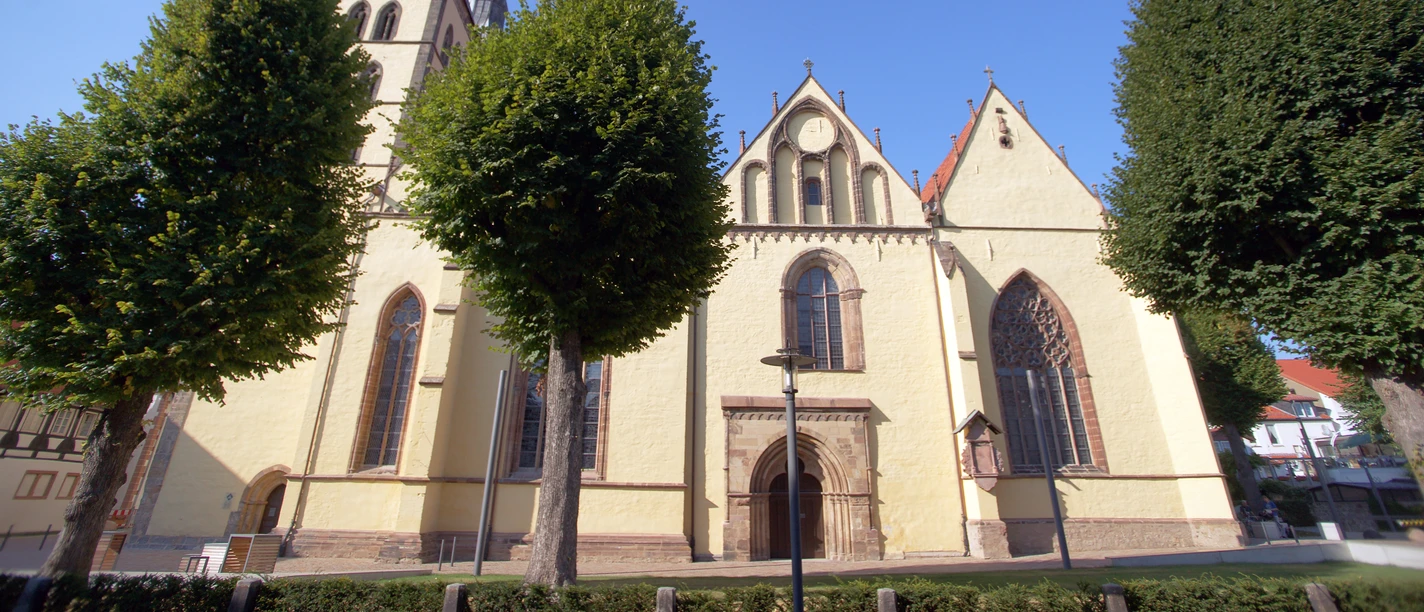 Kirche St. Nicolai Die Kirche St. Nicolai in Lemgo mit imposantem Turm ist von Bäumen umgeben und bei blauem Himmel sichtbar.