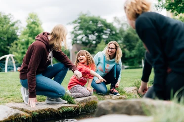 Bielefeld Kinder entdecken ihre Stadt.jpg Vier Personen, darunter zwei Erwachsene und zwei Kinder, genießen gemeinsam die Natur in einem Park.