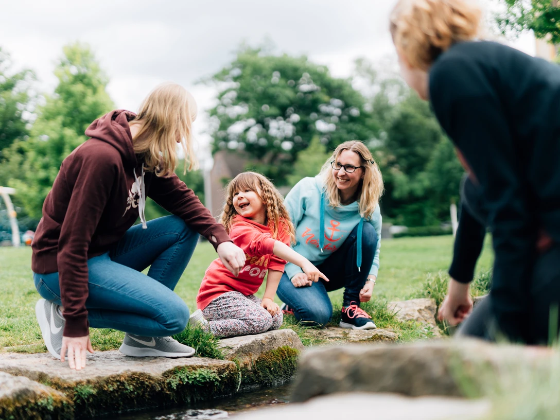 Bielefeld Kinder entdecken ihre Stadt.jpg Vier Personen, darunter zwei Erwachsene und zwei Kinder, genießen gemeinsam die Natur in einem Park.