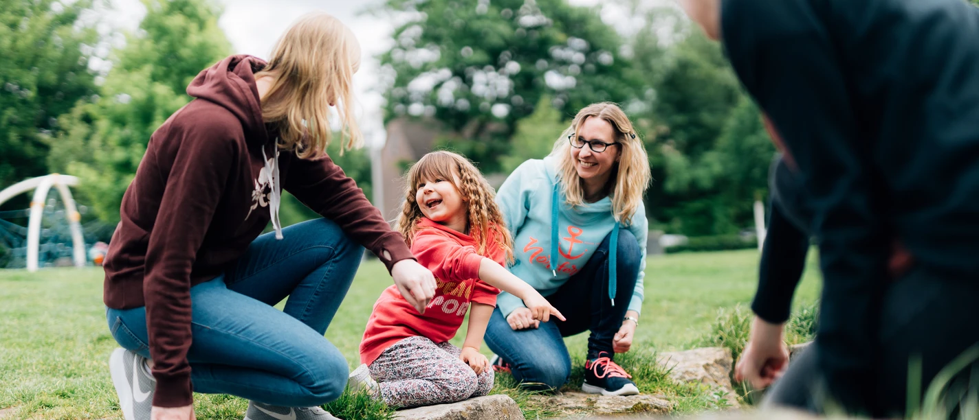 Bielefeld Kinder entdecken ihre Stadt.jpg Vier Personen, darunter zwei Erwachsene und zwei Kinder, genießen gemeinsam die Natur in einem Park.
