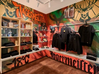 Jägermeister Fanshop Verkaufsecke mit Jägermeister Kleidung, gestaltet mit GraffitiSales corner with Jägermeister clothing, designed with graffitiSalgshjørne med Jägermeister-tøj, designet med graffitiVerkoophoek met Jägermeister kleding, ontworpen met graffiti