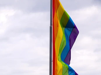 Cologne Pride Eine bunte Regenbogenflagge weht im Wind vor bewölktem Himmel.A colorful rainbow flag flies in the wind against a cloudy sky.