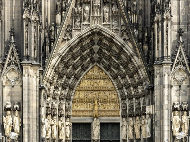 Kölner Dom Detailreiche gotische Fassade des Kölner Doms mit kunstvoll verzierten Statuen und steinerner Ornamente.