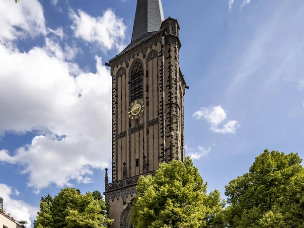 Sankt Severin Sankt Severin in Köln zeigt sich auf dem Bild als majestätische Kirche mit einem hohen Turm, umgeben von grünen Bäumen und einem blauen Himmel.