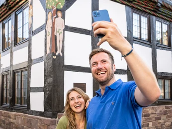 Pärchen mach Selfie von Schnitzwerk von Adam und Eva am FachwerkhausCouple take selfie of carving of Adam and Eve on half-timbered house