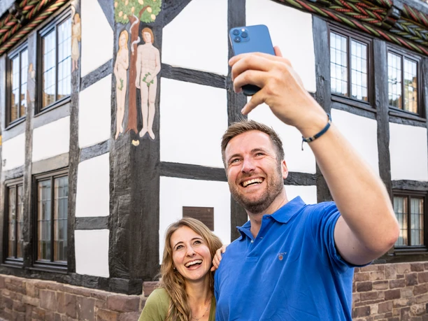 Couple take selfie of carving of Adam and Eve on half-timbered house