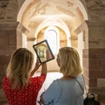 weibliches Pärchen betrachtet auf Tablet die früheren kunstvollen Verzierungen im JohanneschorFemale couple looking at the former ornate decorations in St. John's Choir on a tablet