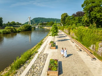 Frauen spazieren auf Weserpromenade mit Brücke im HintergrundWomen walking on the Weser promenade with a bridge in the background