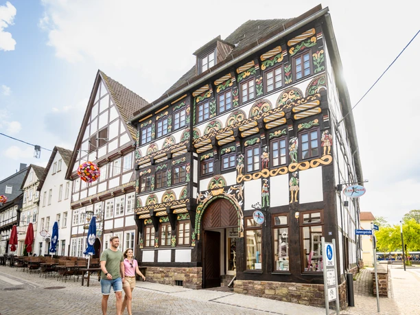 Hoexter-Stadtrundgang-Stadt Hoexter-D. Ketz-2023-044.jpg Pärchen vor aufwendig gestalteter Fachwerkfassade, reich verziert mit Schnitzereien und buntem Anstrich