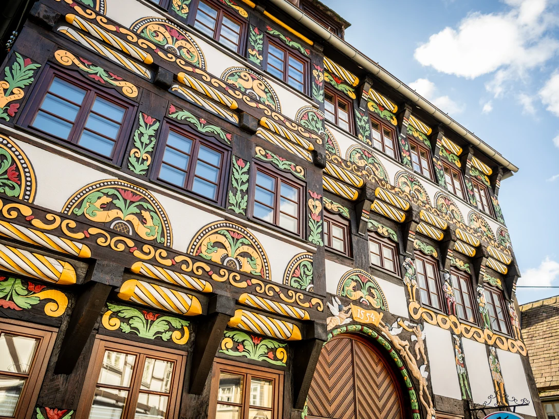 Aufwendig gestaltete Fachwerkfassade, reich verziert mit Schnitzereien und buntem AnstrichElaborately designed half-timbered façade, richly decorated with carvings and colorful paint