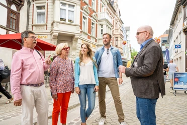 City guide explains history to guests in front of historic buildings in Höxter
