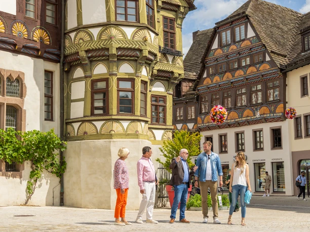 Stadtführer erklärt Gästen die Geschichte vor historischen Gebäuden in HöxterCity guide explains history to guests in front of historic buildings in Höxter