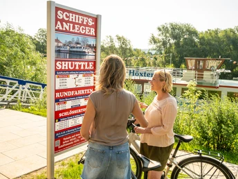 Hoexter-Schiffsanleger-Stadt Hoexter-D. Ketz-2023-254.jpg Zwei Frauen schauen interessiert auf den Fahrplan des Ausflugsschiffes an der WeserTwo women look with interest at the timetable of the excursion boat on the Weser