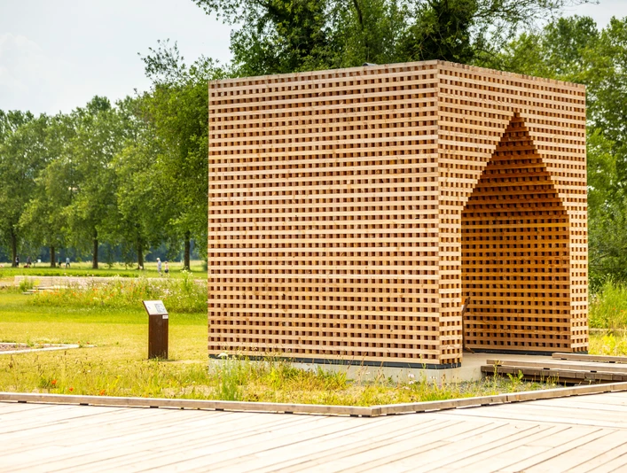 Holzkubus aus kreuzweise geschichteten Holzlatten im Archäologiepark