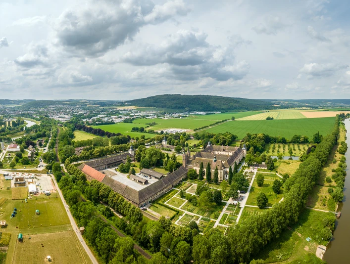 Hoexter-Kloster Corvey-Stadt Hoexter-D. Ketz-2023-442.jpg Luftaufnahme des Klosters Corvey in Höxter, umgeben von Grünflächen und einem Fluss.