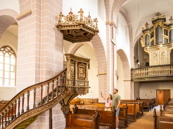 Besucher betrachten schmuckvolle Kanzel mit Alabasterrelief in Kilianikirche