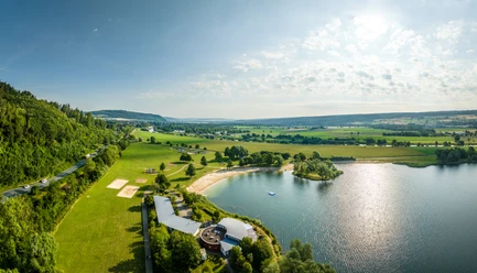 Luftaufnahme des Badesees der Freizeitanlage Höxter-Godelheim mit Sandstrand und Sanitärgebäuden