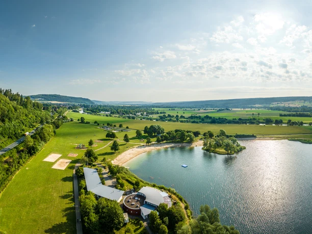 Luftaufnahme des Badesees der Freizeitanlage Höxter-Godelheim mit Sandstrand und Sanitärgebäuden
