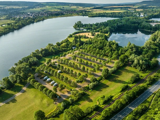 Luftaufnahme des Badesees der Freizeitanlage Höxter-Godelheim mit Wohmobilstellplatz in der Mitte des Bildes