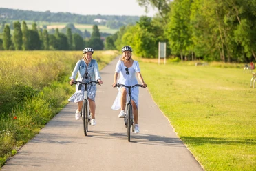 Hoexter-Freizeitanlage Godelheimer See-Stadt Hoexter-D. Ketz-2023-219.jpg Zwei Frauen radeln auf dem Weser-Radweg entlang eines Badesees