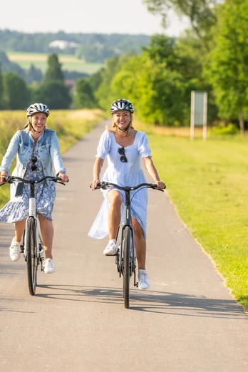 Hoexter-Freizeitanlage Godelheimer See-Stadt Hoexter-D. Ketz-2023-219.jpg Zwei Frauen radeln auf dem Weser-Radweg entlang eines Badesees