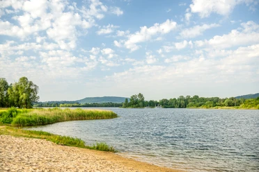 Badesee mit grünen Uferrändern auf beiden Seiten