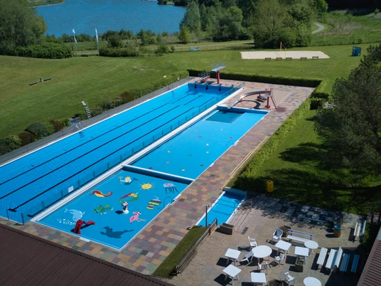 Freibad Schieder Großes Freibad mit Schwimm- und Planschbecken, umgeben von grüner Landschaft und Spielbereichen.