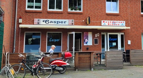Restaurant Casper_Silvana Dust_20230706_1980X1080.jpg Außenansicht eines Backsteingebäudes mit Schild "Casper" über dem Eingang des Restaurants/Bistros