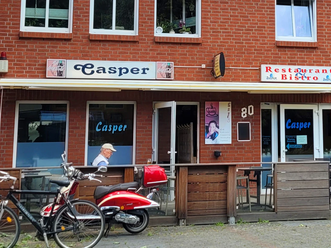 Restaurant Casper_Silvana Dust_20230706_1980X1080.jpg Außenansicht eines Backsteingebäudes mit Schild "Casper" über dem Eingang des Restaurants/Bistros
