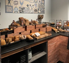 Vielfältige Brotauswahl in einem Buffet, mit verschiedenen Sorten liebevoll auf Holzregalen präsentiert.