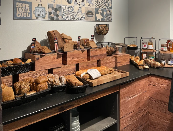 Vielfältige Brotauswahl in einem Buffet, mit verschiedenen Sorten liebevoll auf Holzregalen präsentiert.