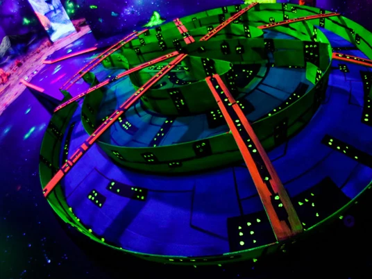 Schwarzlichtgolf.jpg Leuchtendes, futuristisches Golfparcoursdesign in Schwarzlicht, umgeben von leuchtenden Raumthemen.