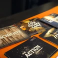 Room Fox Osnabrück.jpg Werbekarten von raumbezogenen Abenteuerspielen auf einem orangefarbenen Tisch arrangiert.