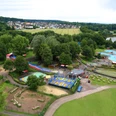 KN7A0233.jpg Luftaufnahme eines Freizeitparks mit Wasserrutschen, Spielplätzen, umgeben von Wald und See.
