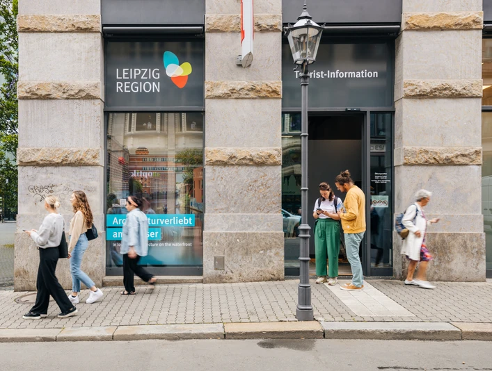 Eingang zur Tourist-Information Leipzig - Besucherberatung und Service Fassade und Haupteingang der Tourist-Information Leipzig in der Katharinenstraße 8, einige Touristen stehen vor dem Eingang und schauen sich Informationsmaterial anFasada i wejście główne do Informacji Turystycznej w Lipsku na Katharinenstraße 8, kilkoro turystów stoi przed wejściem i przygląda się materiałom informacyjnymThe façade and main entrance of the Leipzig Tourist Information Office, Katharinenstraße 8. Several tourists are standing in front of the entrance and looking at informational materialFaçade et entrée principale de l'office de tourisme de Leipzig au 8 rue Katharinenstraße, quelques touristes se tiennent devant l'entrée et consultent de la documentationFasáda a hlavní vchod do turistického informačního centra v ulici Katharinenstraße 8, před vchodem stojí několik turistů prohlížejících si informační materiál
