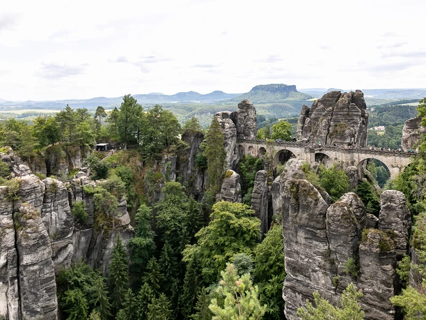 Basteibrücke Steinbrücke zwischen beeindruckenden Felsformationen der Sächsischen Schweiz, bewaldete Umgebung.
