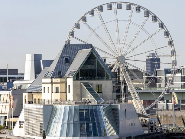 Ein Riesenrad steht neben dem Gebäude des Schokoladenmuseums in Köln.