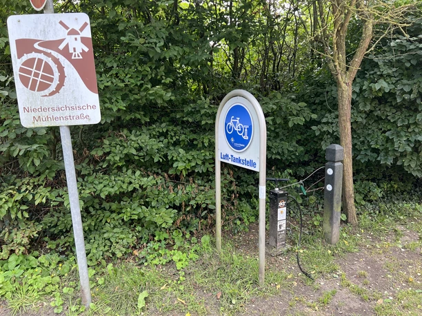 Lufttankstelle Martfeld Lufttankstelle an einem Fahrradweg, umgeben von dichtem Laub und einem Schild der Mühlenstraße.