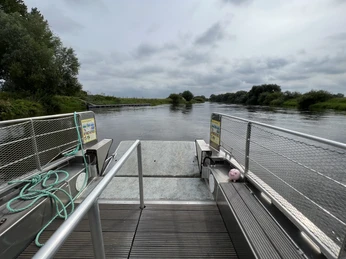 Solarbetriebene Fähre auf der Weser in Otersen mit Anleger, umgeben von grüner Flusslandschaft.