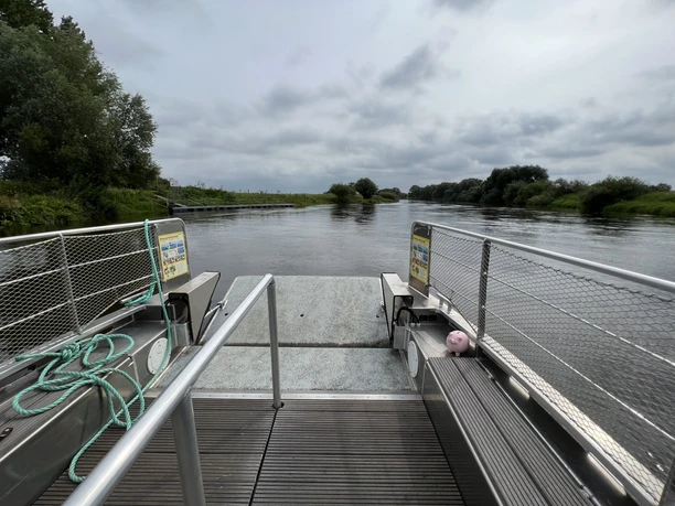 Solarbetriebene Fähre auf der Weser in Otersen mit Anleger, umgeben von grüner Flusslandschaft.