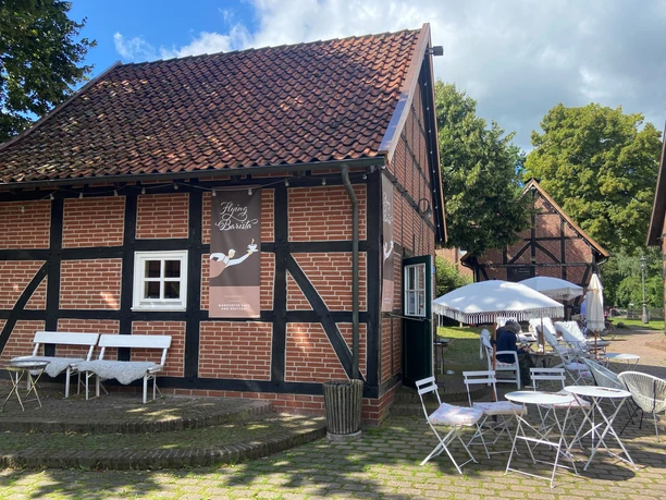 Historic half-timbered building with "Flying Barista" sign, surrounded by cozy outdoor areas.