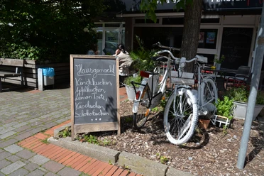 Café Fensterplatz im Herzen von Enger Kleines Café in Enger mit Fahrrad vor der Tür und Tafel mit hausgemachten Kuchenvarianten.