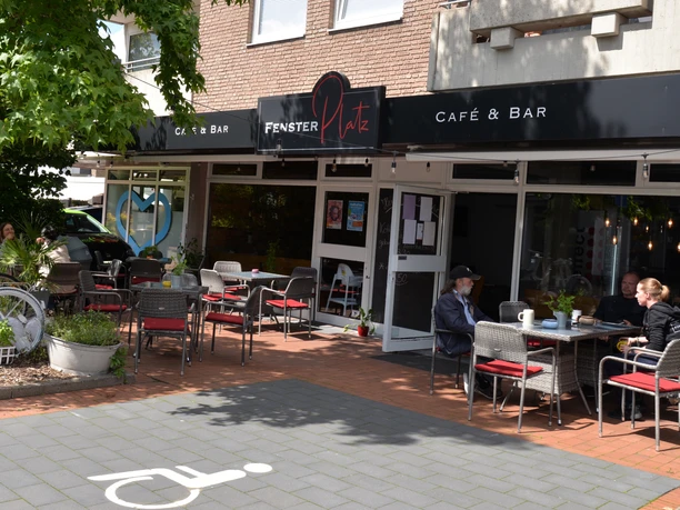 Café Fensterplatz Außenbereich eines Cafés mit mehreren Tischen und Gästen vor dem Café Fensterplatz.
